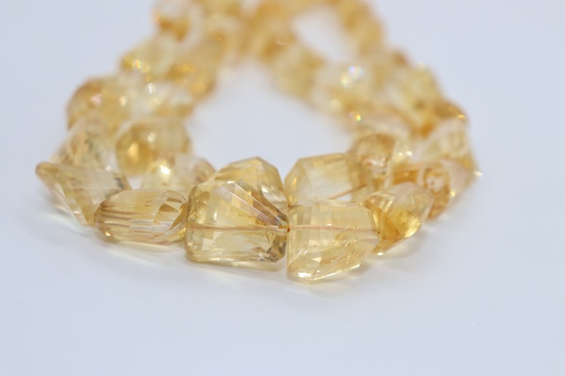 May include: A strand of faceted, golden citrine beads. The beads are irregular in shape and have a translucent, glassy appearance.