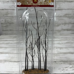 May include: A plastic package containing a set of black twig-like branches with a brown base. The branches are frosted with a white shimmer. The package has a label that reads "Handcrafted Village Snow-Covered Ornament".
