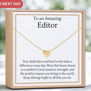 May include: A gold heart charm necklace in a gift box with a message that reads "To an Amazing Editor. Your dedication and hard work make a difference every day. Wear this heart charm as a symbol of your passion, strength, and the positive impact you bring to the world. Keep shining bright in all that you do."