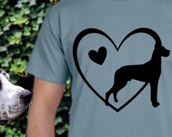 May include: A light blue t-shirt with a black silhouette of a dog inside a heart. The heart has a smaller heart inside it.
