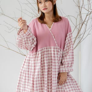 May include: A pink and white gingham dress with a pink bodice and long sleeves. The dress has a gathered skirt and a V-neckline.