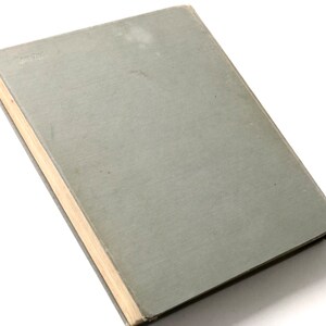 May include: A gray hardcover book with a light brown spine. The book is closed and lying on a white surface.