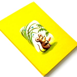 May include: A yellow book cover with a cartoon illustration of a mouse holding a piece of wheat in a field of green grass.