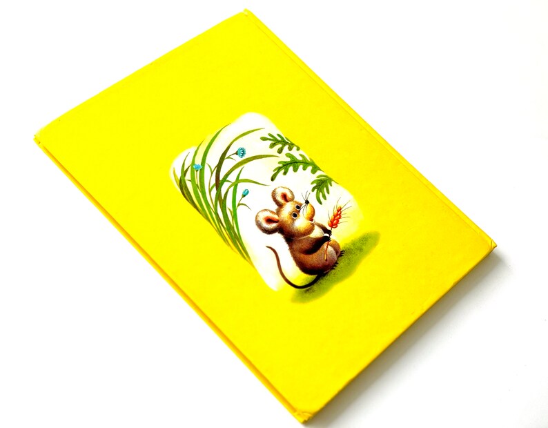 May include: A yellow book cover with a cartoon illustration of a mouse holding a piece of wheat in a field of green grass.