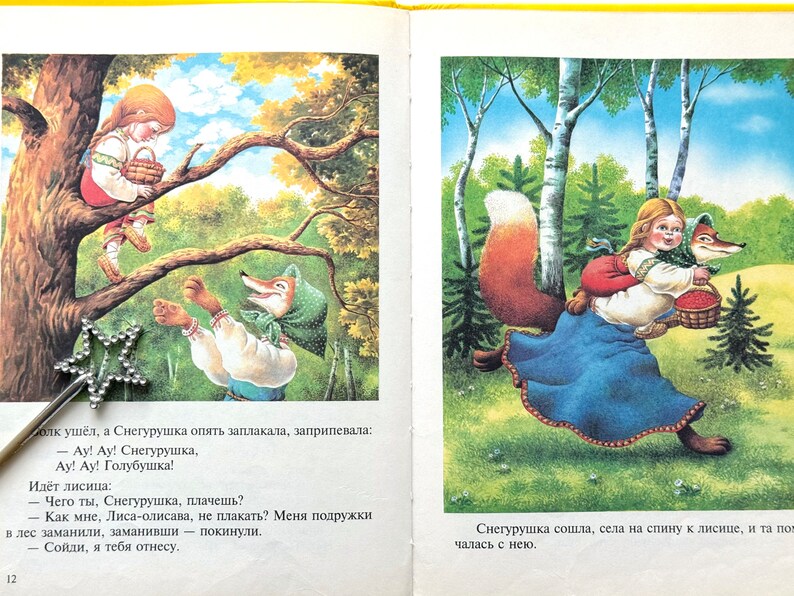 May include: A red fox wearing a blue dress and a green headscarf carries a young girl in a blue dress and a red headscarf through a forest. The girl is holding a basket of red berries. The fox has a bushy red tail.