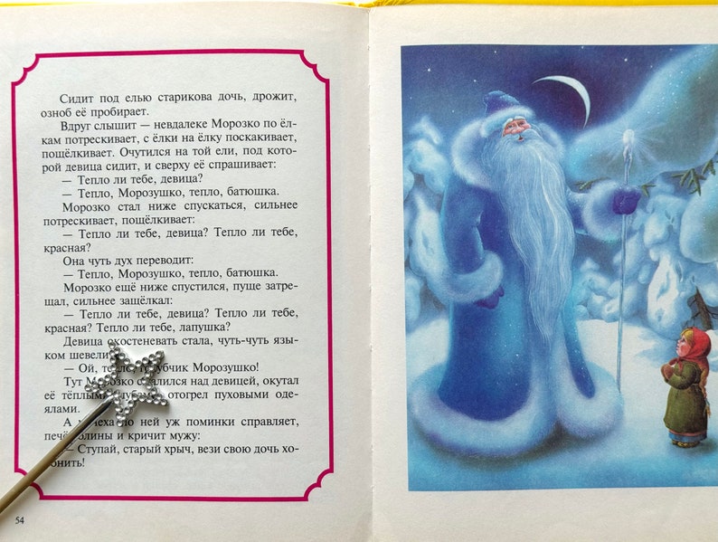 May include: A blue-clad figure with a long white beard stands in a snowy landscape, holding a staff. A small girl in a red hat and green coat looks up at the figure. The text in the image reads: "Тепло ли тебе, девица?"