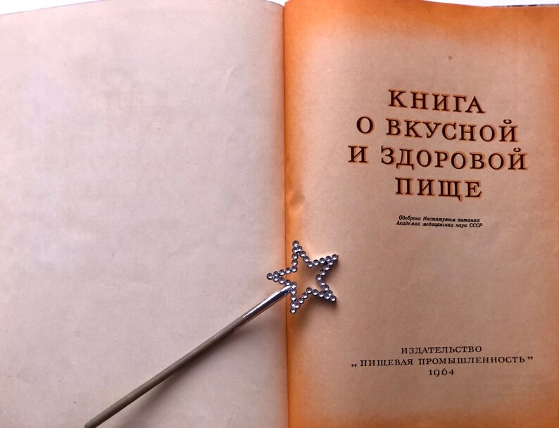 May include: A vintage book titled "Книга о вкусной и здоровой пище" (Book of Delicious and Healthy Food) with a silver star-shaped bookmark. The book was published in 1964 by "Пищевая промышленность" (Food Industry).