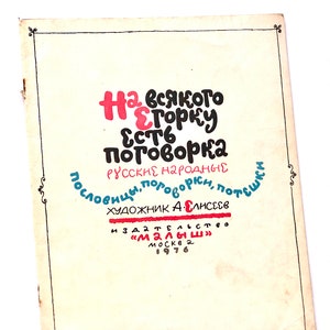 Può includere: Una copertina di libro vintage con un titolo colorato "На всякого есть поговорка" (che significa "Per ognuno c'è un proverbio") in russo. La copertina include anche il testo "Русские народные пословицы, поговорки, потешки" (che significa "Proverbi, detti e rime popolari russi") e "Художник А. Елисеев" (che significa "Artista A. Eliseev"). Il libro è stato pubblicato da "Малыш" (che significa "Piccolo") a Mosca nel 1976.
