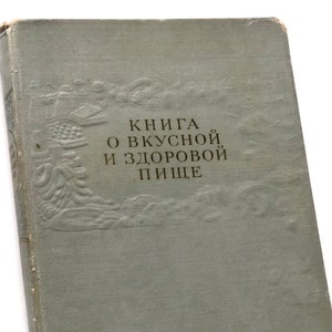 May include: A vintage book with a light blue cover and embossed details. The title reads "Книга о вкусной и здоровой пище" which translates to "Book about tasty and healthy food".