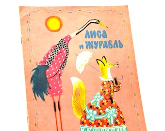 May include: Vintage children's book cover with a pink background and illustrations of a crane and a fox. The crane wears a pink polka-dot coat, and the fox is in a floral dress. The text "Лиса и журавль" is in blue.