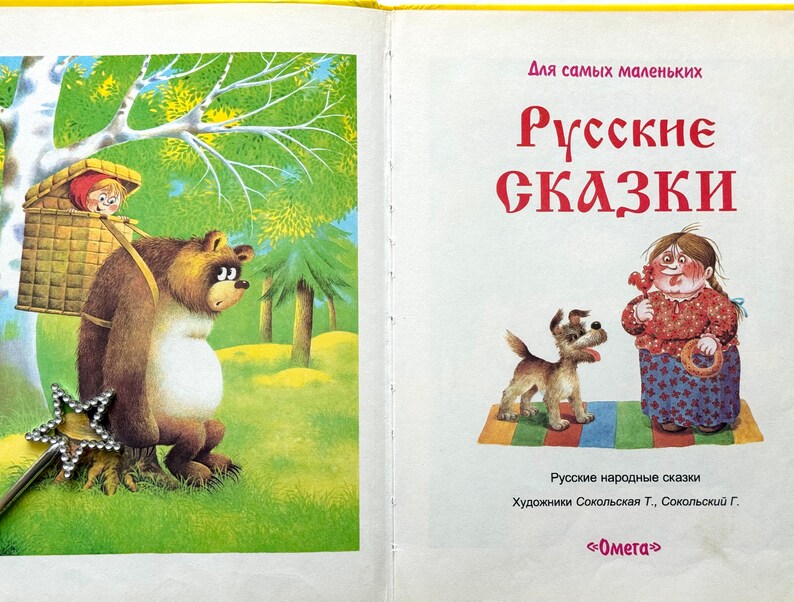 May include: A vintage children's book cover featuring a brown bear carrying a basket with a girl inside. The bear is standing in a forest setting with a green background. The book title is "Russian Fairy Tales" in large, bold letters. The book is for young children.