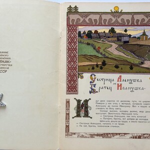 May include: An open book with a colorful illustration of a rural landscape, featuring a winding road, buildings, and a church. The text in Russian reads "Sister Alyonushka and Brother Ivanushka."