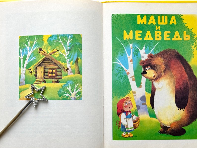 May include: A children's book cover with a colorful illustration of a girl in a red hood and a bear. The title of the book is "Masha and the Bear" in Russian.