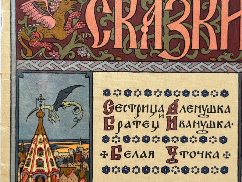 May include: Vintage book cover with ornate lettering and illustrations. The title, in large orange letters, is above a decorative border. Below, a framed illustration depicts a dragon over a building. Text in Russian script is also present.