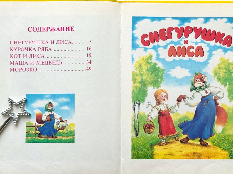 May include: A vintage children's book cover featuring an illustration of a girl in a red dress and a fox in a blue dress dancing in a forest. The title of the book is "СНЕГУРУШКА И ЛИСА" which translates to "Snow Maiden and the Fox".
