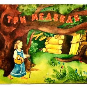 May include: A vintage children's book cover with a watercolour illustration. The title "Три медведя" (Three Bears) is in red letters. A girl in a blue dress walks with a basket and a stick near a log cabin and a large tree.