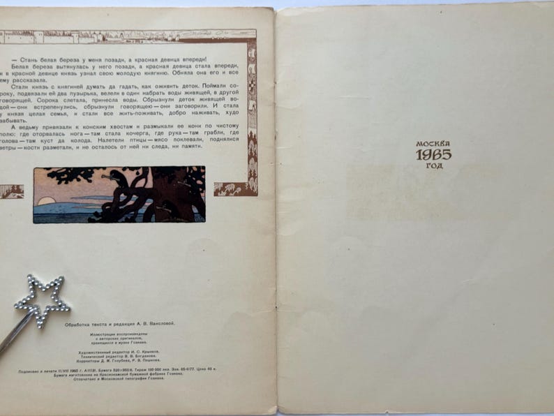 May include: An open book with text in Russian and an illustration of a tree and sunset. The right page has the text "MOCKBA 1965 год" printed in brown. A silver star-shaped wand is in the lower left corner.