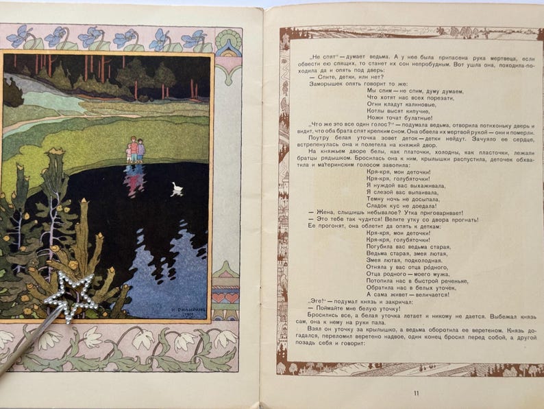 May include: An illustrated page from a children's book, featuring a colorful landscape scene with figures near a lake and a white swan. A silver star-shaped wand rests on the page.