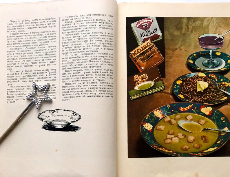May include: A vintage cookbook open to a page with a recipe for soup. The page features illustrations of bowls of soup, a plate of buckwheat porridge, and a glass of juice. The cookbook also features advertisements for canned goods, including 'Kučero' and 'Гречневая'.