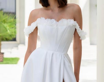 Vestido de novia artesanal con hombros descubiertos, apliques florales y abertura.