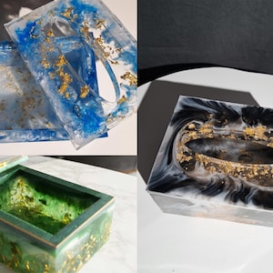 Puede incluir: Cajas decorativas de resina en tonos azules, verdes y negros, con detalles de pan de oro. El conjunto incluye una tapa para caja de pañuelos y una caja rectangular. La resina tiene un efecto veteado.