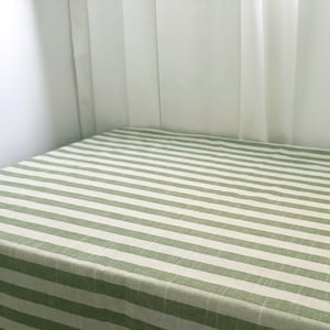 May include: A green and white striped tablecloth with a linen texture.