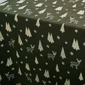 May include: A dark green tablecloth with a white Christmas pattern featuring trees, snowflakes, and deer.