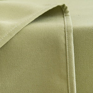 May include: Close-up of a light green fabric with a subtle textured pattern. The fabric has a seam running down the side.