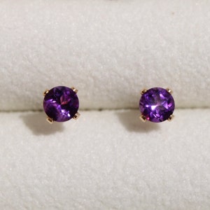 Op de afbeelding: Een paar amethist oorbel studs met gouden instellingen.