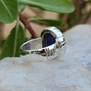 May include: A silver ring with a blue gemstone set in a textured band.