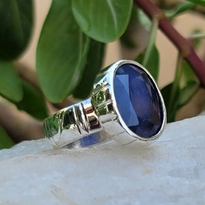 May include: A silver ring with a dark blue oval gemstone. The ring has a textured band.