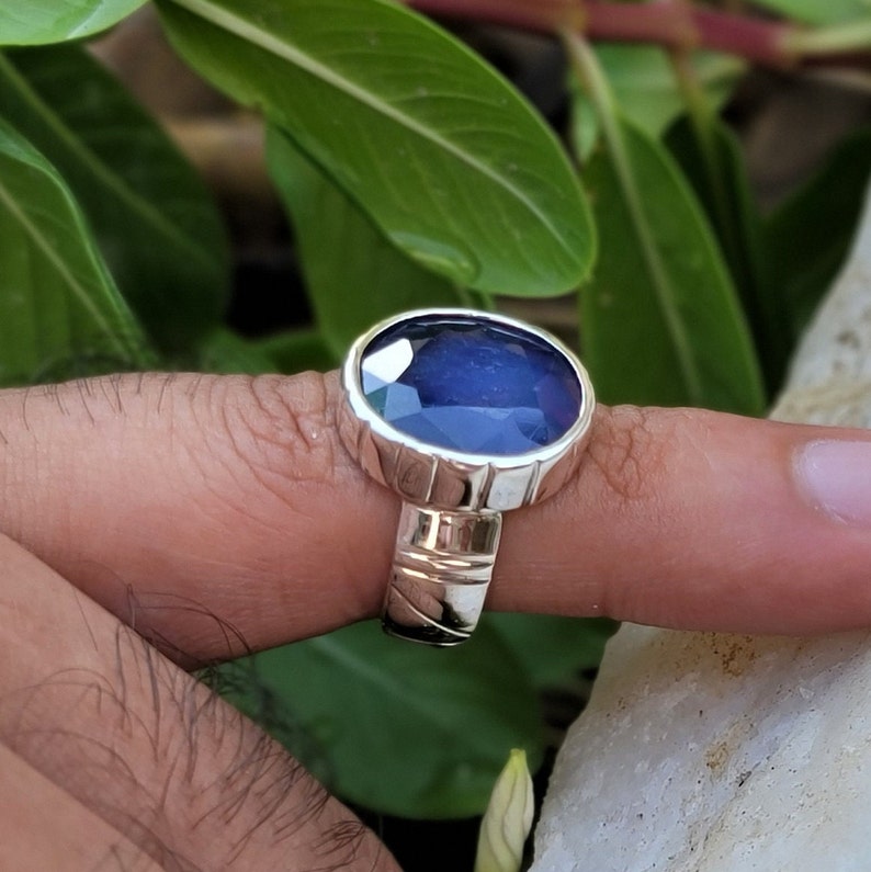 May include: A silver ring with a dark blue oval gemstone set in a textured band.