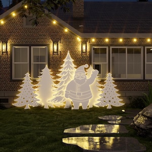 Peut inclure: Scène nocturne d'une maison décorée pour Noël. Des découpes éclairées du Père Noël et de sapins sont dans le jardin. Des guirlandes lumineuses et des lanternes murales ajoutent à l'ambiance festive. La maison est en briques.