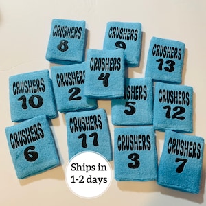 May include: Twelve blue wristbands with the word "CRUSHERS" and a number from 1 to 13 printed in black.