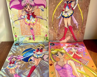 May include: Four Sailor Moon trading cards featuring colorful anime illustrations. The cards depict various characters in action poses, with vibrant pink, yellow, and blue color schemes. Each card has Japanese text and decorative borders.