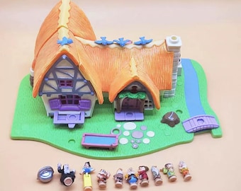 May include: A colorful miniature cottage playset with an orange thatched roof, blue accents, and a green base. Includes miniature figures of Snow White and the Seven Dwarfs, along with other accessories. A charming collectible toy.