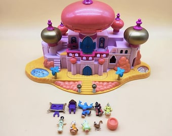 Könnte beinhalten: Ein Vintage-Spielset mit einem rosa-goldenen Palast mit einer großen Kuppel und mehreren kleineren Kuppeln. Das Spielset enthält Miniaturfiguren von Charakteren und Zubehör. Die Basis ist gelb mit einem kleinen Pool und Palmen.