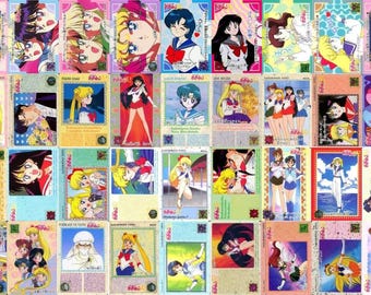 May include: A collection of rectangular trading cards featuring various anime characters from Sailor Moon, displaying colorful illustrations of the protagonists in different poses, outfits, and settings, with Japanese text printed on each card.