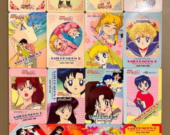 May include: A collection of sixteen rectangular Sailor Moon R trading cards featuring various anime character illustrations, colorful backgrounds, and Japanese text. Each card displays distinct scenes, character portraits, and the Sailor Moon R logo.
