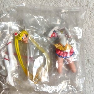 May include: A disassembled Sailor Moon anime character figurine inside a clear plastic bag. The set includes a head with long blonde hair, a torso with a white top and yellow and pink skirt, and a separate white boot, all made of painted plastic.