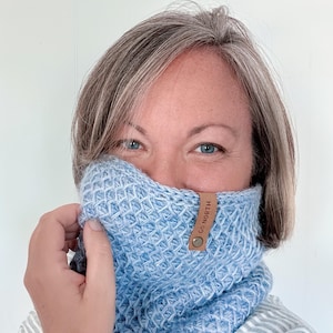 May include: A light blue knitted neck warmer with a brown leather tag that says "GO NORTH".