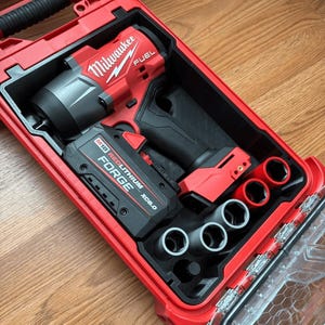 Könnte beinhalten: Ein rotes Milwaukee FUEL Schlagschrauber-Set in einem roten Hartschalenkoffer. Das Set enthält den Schlagschrauber, einen Akku und mehrere Steckschlüssel. Der Koffer ist geöffnet und zeigt die Werkzeuge, die ordentlich im schwarzen Innenraum angeordnet sind.