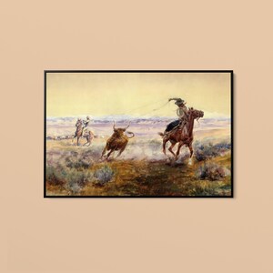 Könnte beinhalten: Ein gerahmtes Querformat-Gemälde, das eine Westernszene mit zwei Reitern in einer Wüstenlandschaft zeigt. Ein Reiter im Vordergrund wirft ein Lasso auf einen braunen Stier, während ein weiterer Reiter in der Ferne zu sehen ist. Das Bild zeigt erdige Töne, staubiges Gelände und ferne Berge unter einem blassen Himmel.