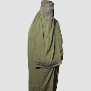 May include: Olive green burqa with intricate embroidery on the head covering and sleeves. The garment is a flowing, full-length design, with detailed patterns around the face and wrist areas. The fabric appears to be lightweight.