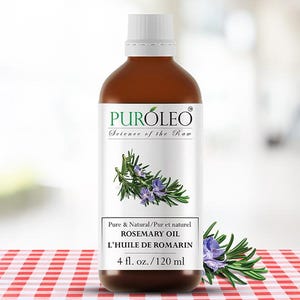 May include: A brown bottle of rosemary oil with a white label displaying the brand name "PURÓLEO" and a rosemary sprig. The label reads "Pure & Natural ROSEMARY OIL" and "120 ml". The bottle is placed on a red and white checkered surface.