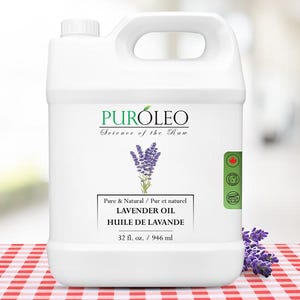 Puede incluir: Un bidón de plástico blanco de aceite de lavanda con asa. La etiqueta dice "PURÓLEO Science of the Raw" y "LAVENDER OIL HUILE DE LAVANDE 946 ml." Una ramita de lavanda está sobre la mesa.