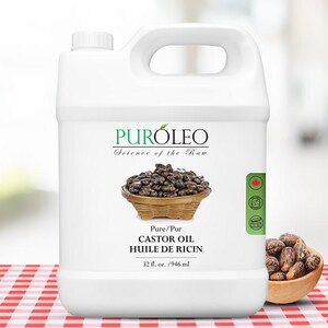 May include: A white plastic jug of PurOleo Castor Oil. The label features a basket of castor beans and the text "Pure/Pur Castor Oil Huile de Ricin 32 fl. oz. / 946 ml." A small wooden bowl of castor beans sits to the right.