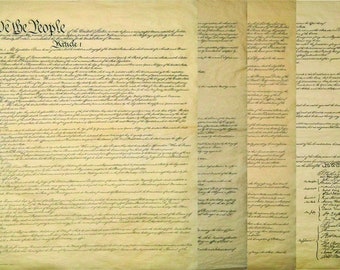 May include: A historical document, the United States Constitution, is displayed. The parchment-like paper features handwritten text in black ink, with the words "We the People" prominently displayed at the top. The document is aged, with visible creases and a yellowed hue.