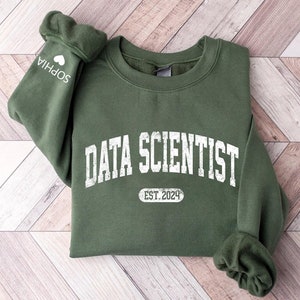 May include: A green sweatshirt with the text "DATA SCIENTIST" in white with a distressed look. Below the text is a white oval with the text "EST. 2024".