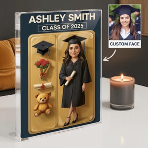 May include: A graduation themed doll-like figure with a custom face, a graduation cap, and a diploma. The figure is standing on a gold background with a teddy bear, a bouquet of red roses, and a diploma scroll. The text "Ashley Smith Class of 2025" is at the top of the image.
